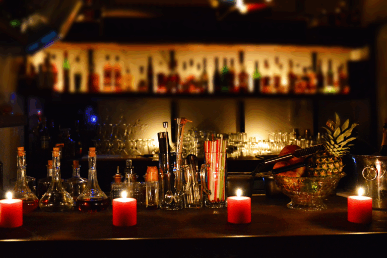 A bar in a nightclub with candles on the bar and bottles in the background