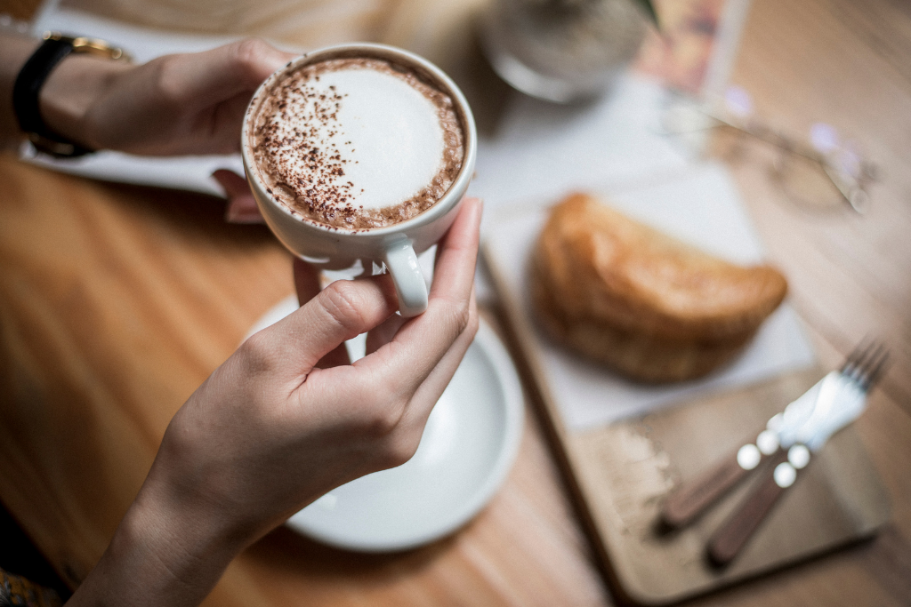 A person holding a cup of coffee in a cafe