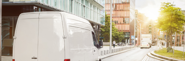 a van outside a building on a sunny day near offices and flats